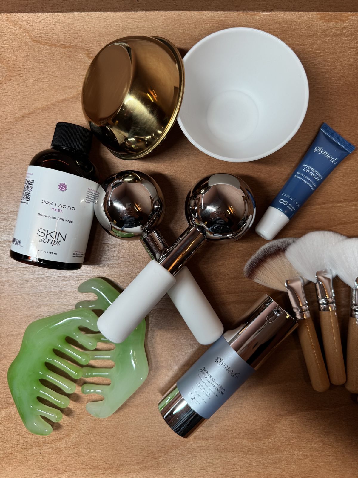 Facial tools and Skin Script products laid out on a wooden table